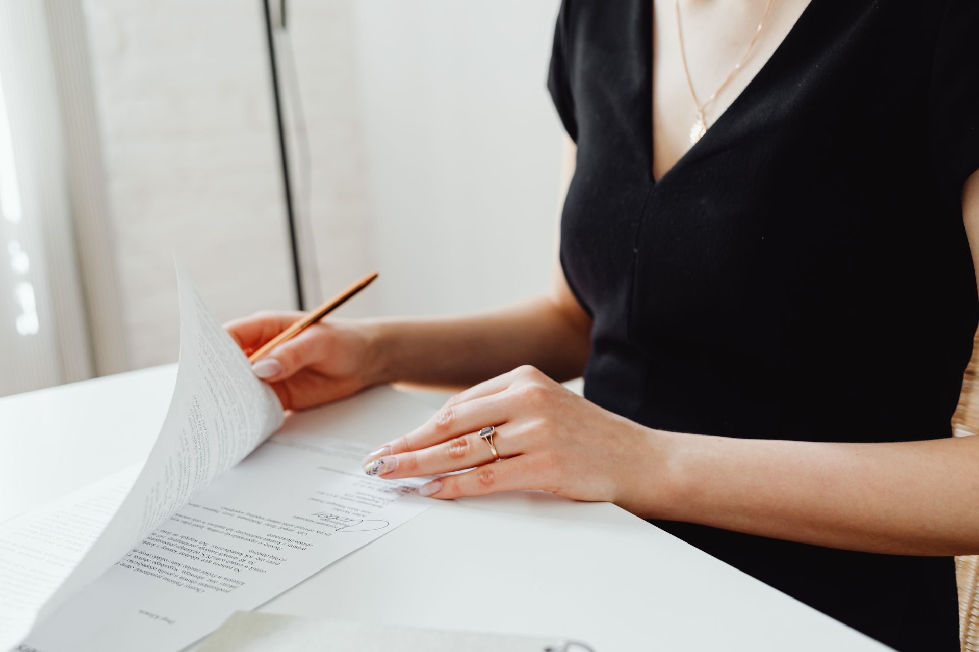A woman looks through a contract with while holding a pen