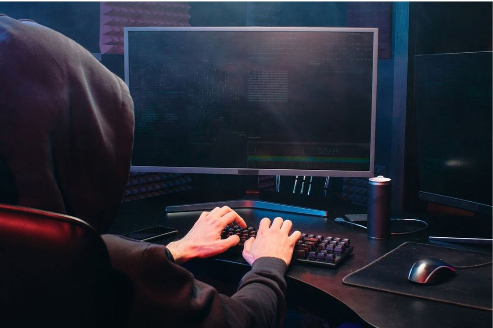 Hacker on laptop with their hood up